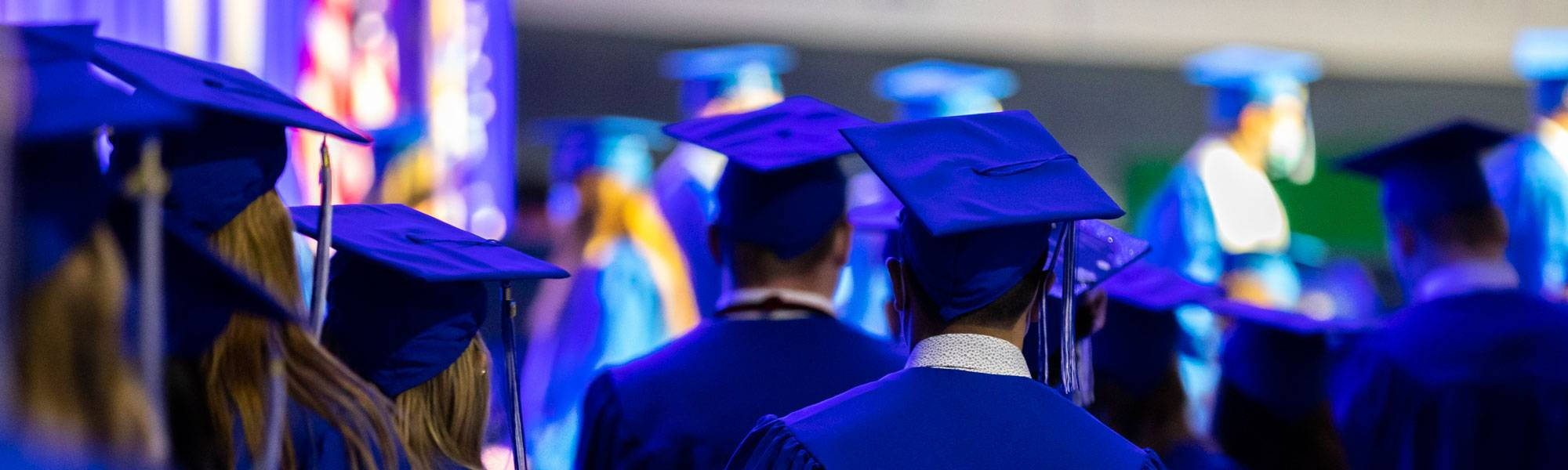 GVSU students wearing blue caps and gowns at a commencement ceremony.
